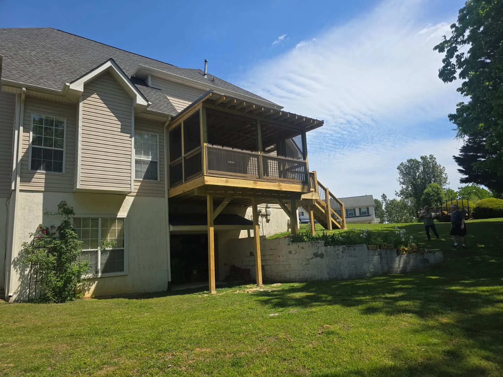Elevated screened deck with a pergola roof and wooden stairs